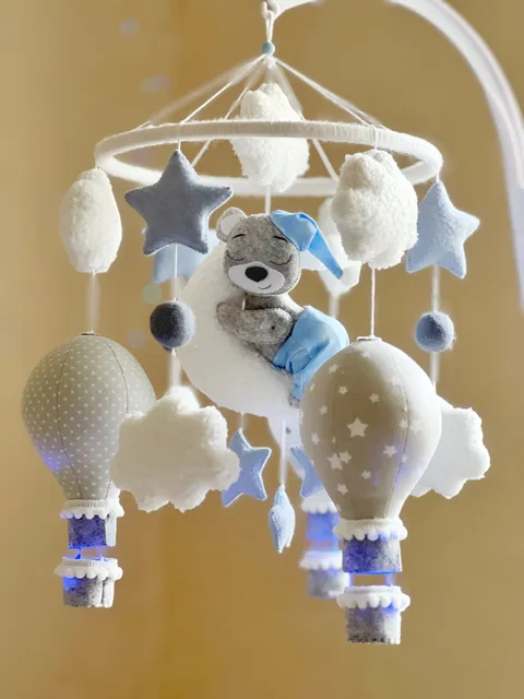 Baby mobile for a crib with balloons and a teddy bear on the moon. The mobile is made of felt, cotton, boucle