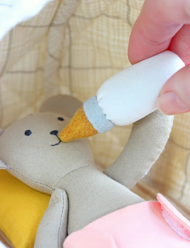 It's so much fun to dress this bear, put it to bed, feed it, or take it along — it fits in a pocket!
Add this tiny bear to your collection of handmade stuffed animals. It has so many adorable accessories, including a cozy hooded sleeping basket, that you're sure to love! The sewing pattern is easy to follow and beginner friendly, with lots of sewing tips and tricks. Clear instructions will guide you through the sewing process from beginning to end and your little one will love their new little friend!