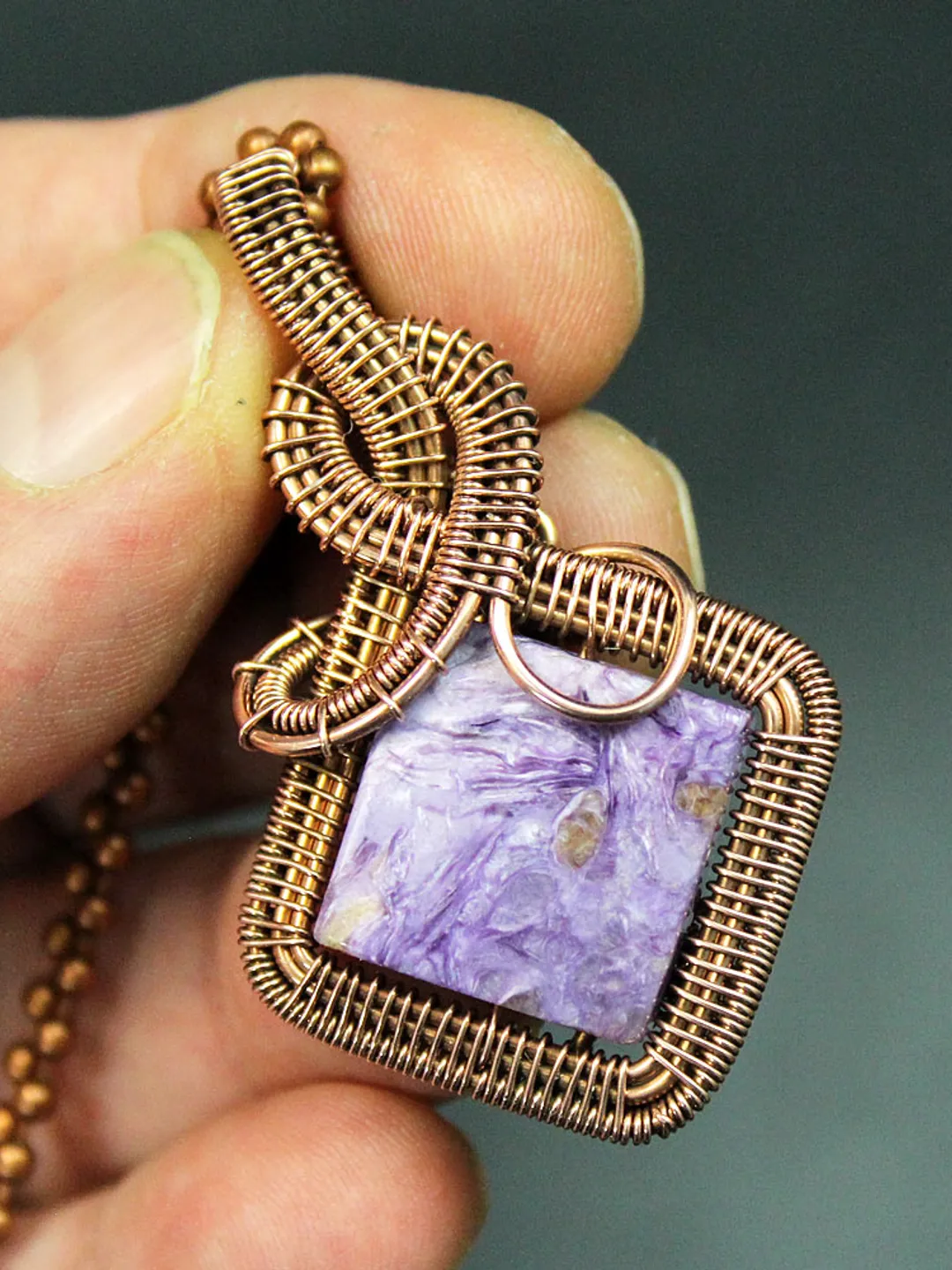 Handmade pendant of natural charoite and copper wire.