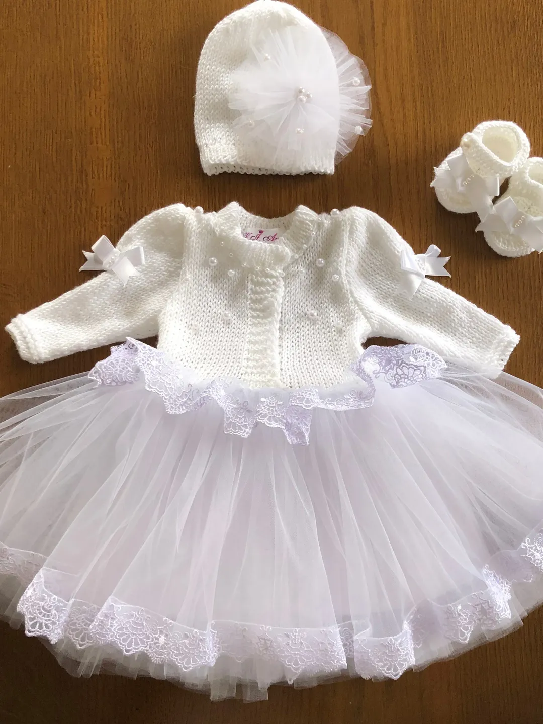 Knit clothing set for baby girl. White, knit dress with lace, pearls and tulle, hat and booties for baby girl.