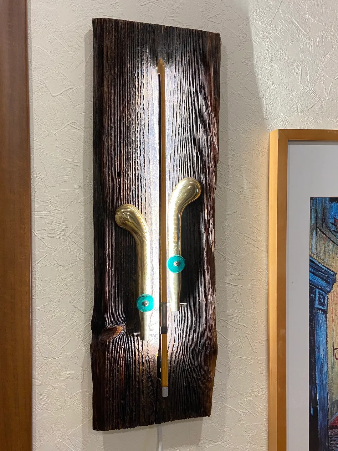 Wall sconce of antiques violin bow and brass pedals from the piano