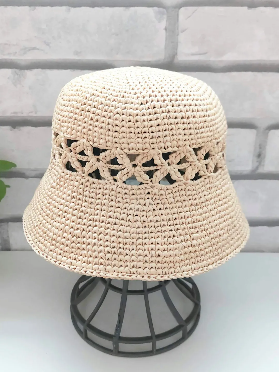 Hat in braided raffia strawwith a crocheted lookHole pattern around crown