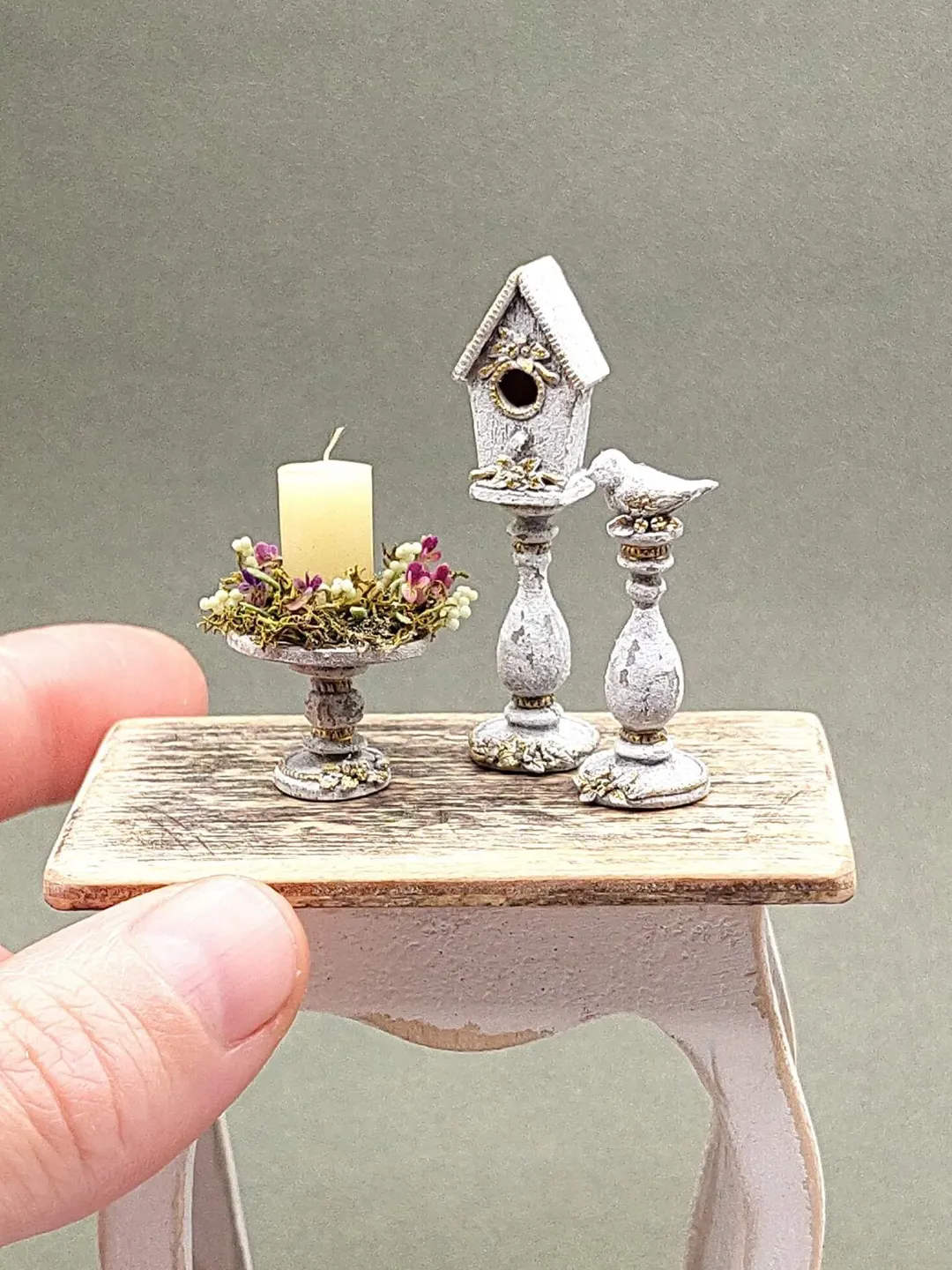 A set of miniature candle holder with a bird, a candlestick with a birdhouse, a pedestal with a candle and a flower arrangement. Miniature 1:12 for a dollhouse