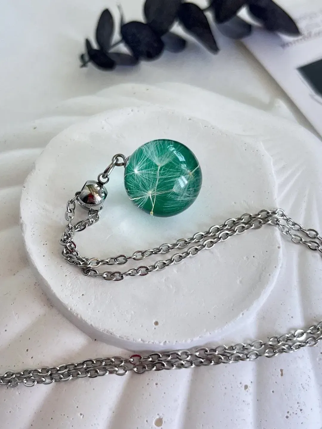 Handmade epoxy resin pendant for women's neck with dandelion fluffs on an emerald background