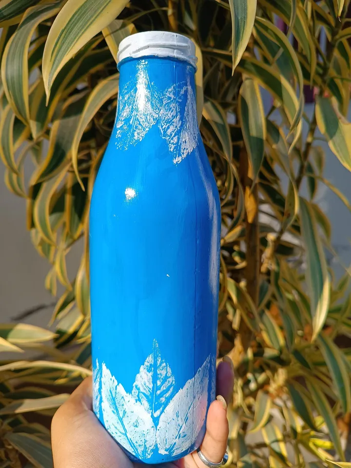Hand painted bottle art with white leaves.