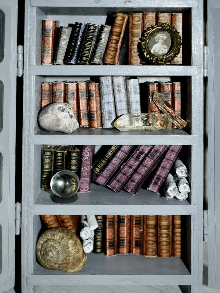 A miniature bookcase with books on a bookshelf between books