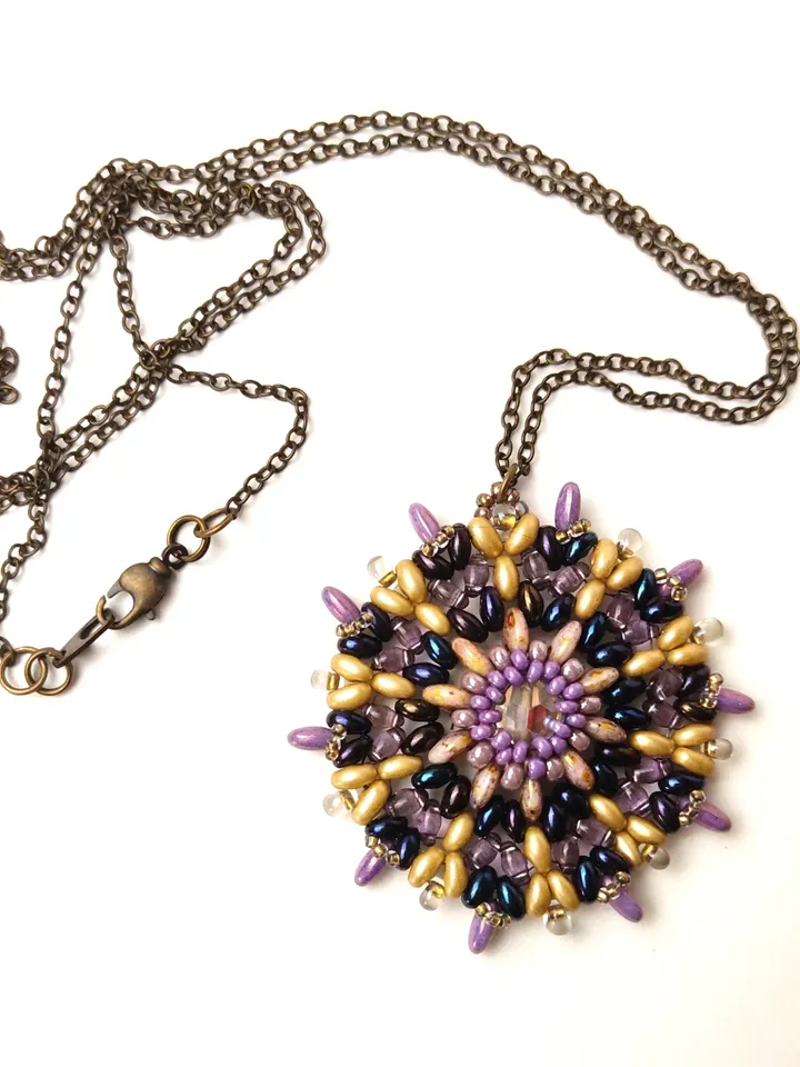 Round lilac-gold openwork beaded pendant with a faceted bead on a chain