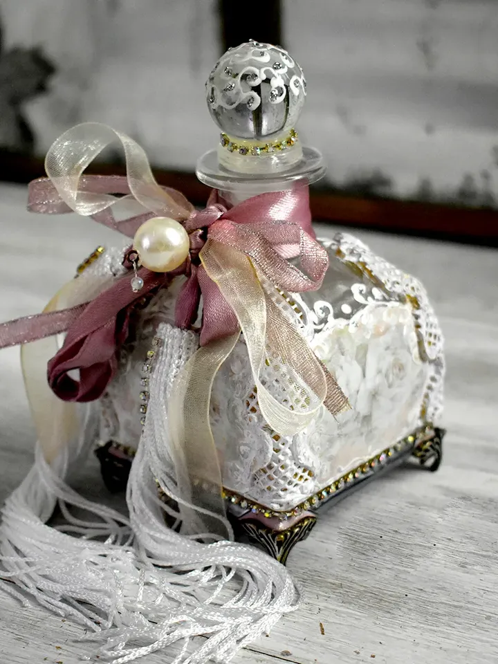 Rose glass bottle for storing perfumes and aroma oils with a voluminous decor