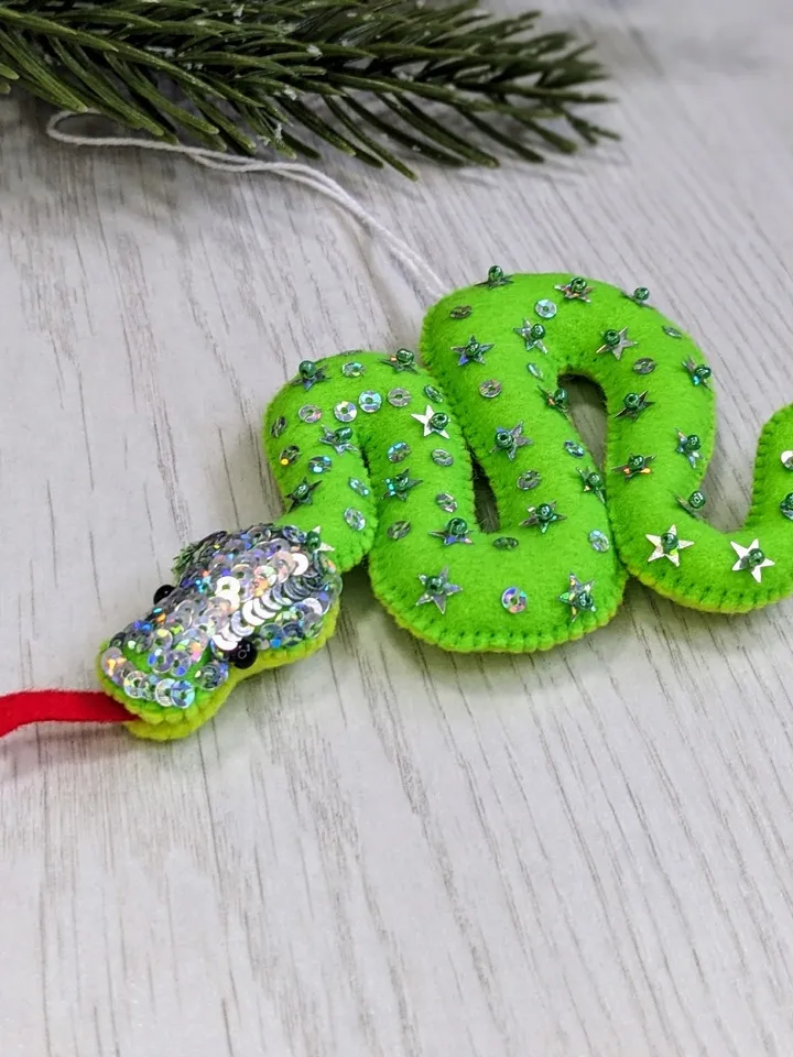 The green snake, the emerald snake, is the symbol of the new year 2025 according to the eastern calendar. Green snake with shiny scales felt Christmas tree decoration