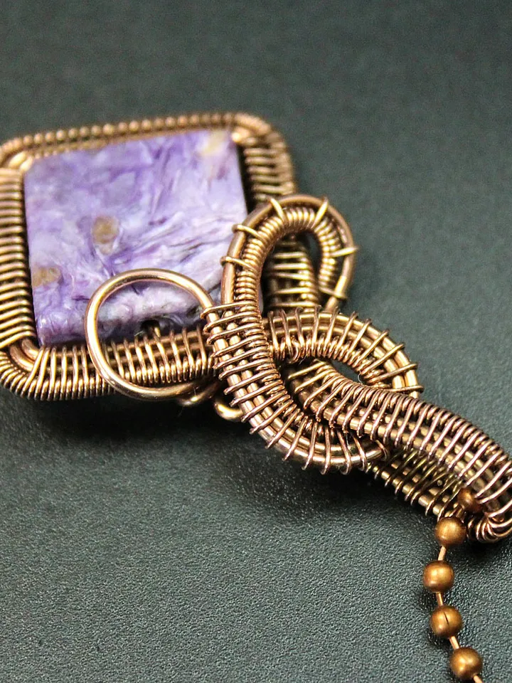 Handmade pendant of natural charoite and copper wire.
