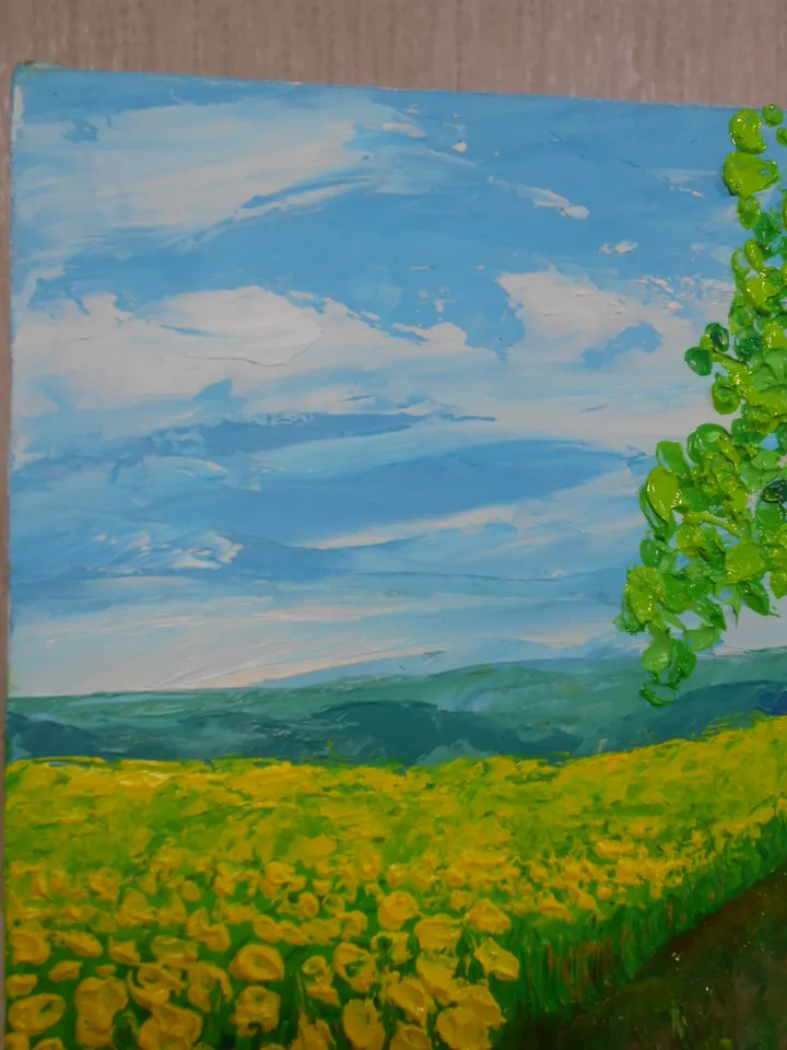 A bright landscape. Mountains in the distance, blue sky with light clouds, a field of yellow flowers, a birch tree. The original painting.