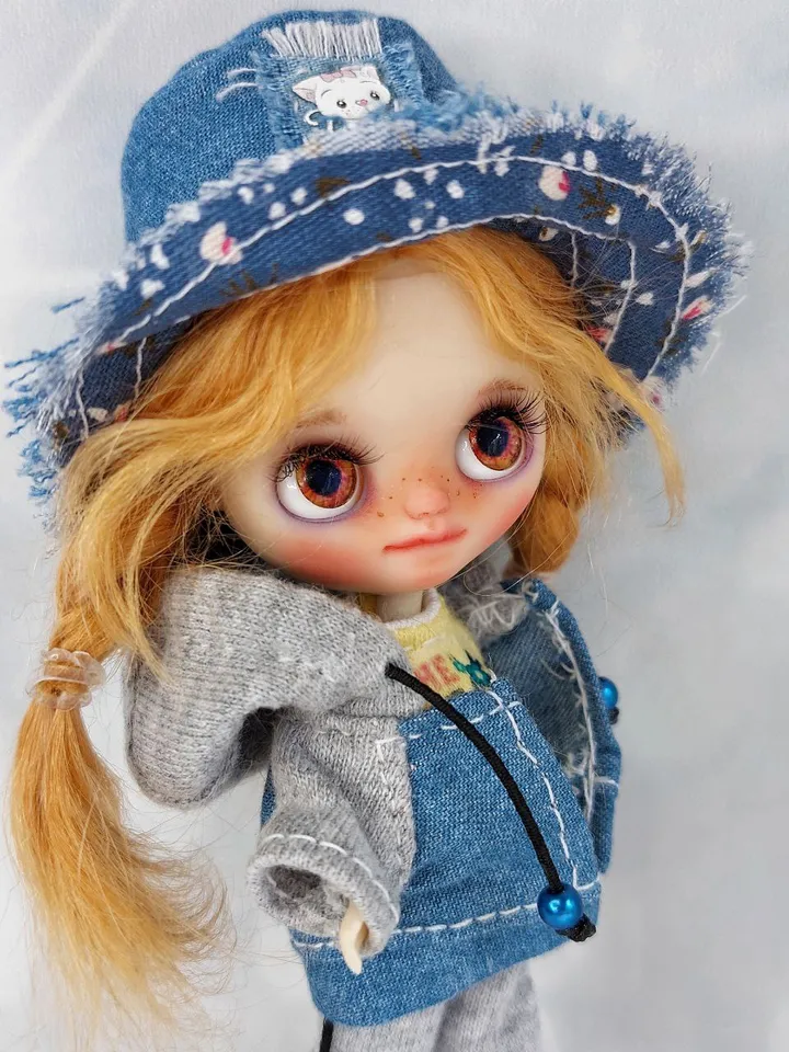A little Blythe doll with red hair and brown eyes. a girl in a denim outfit.