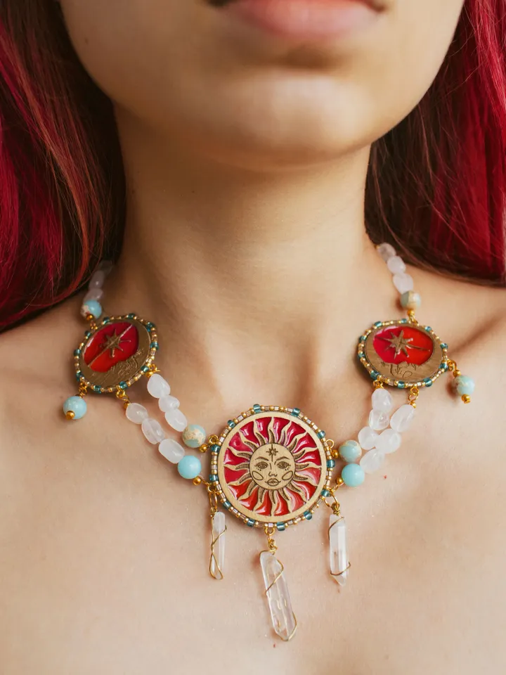 Statement necklace When The Sun Meets The Moon with blue jasper and clear quartz crystals. Gold jewelry with celestial design in sunset red and orange color with beading. Maylina Soul