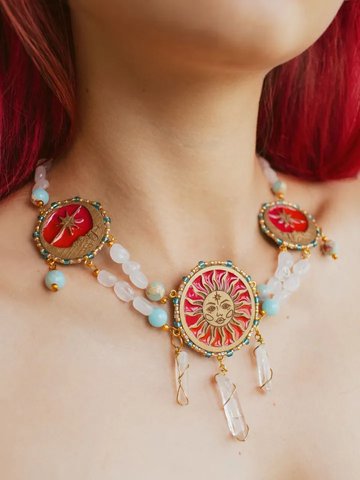 Statement necklace When The Sun Meets The Moon with blue jasper and clear quartz crystals. Gold jewelry with celestial design in sunset red and orange color with beading. Maylina Soul