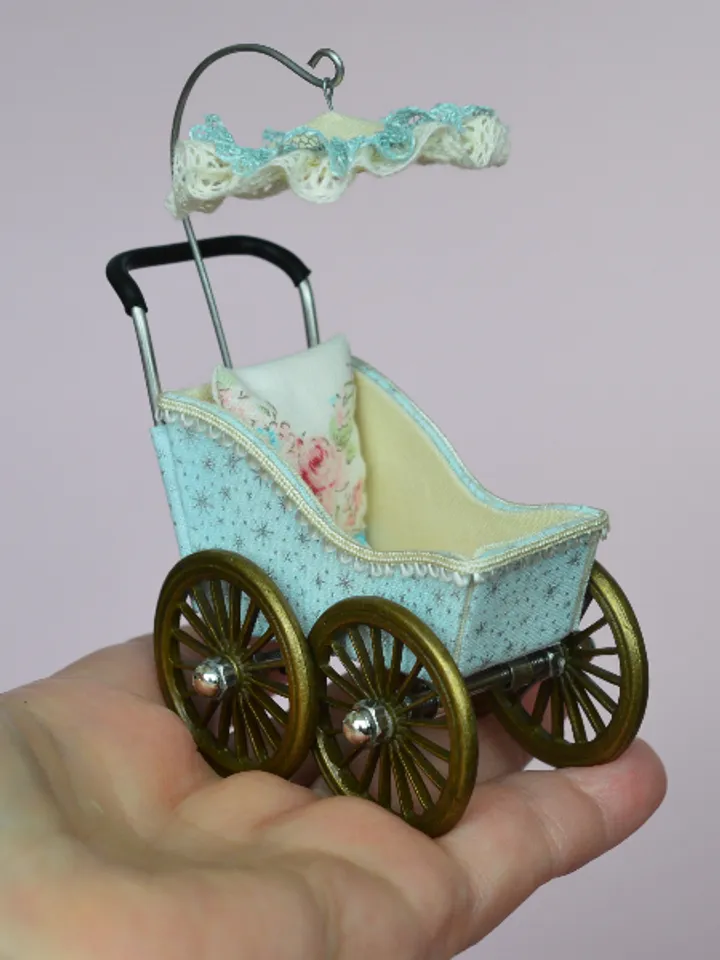 Miniature toy stroller for a little doll. Pram for the little poopsie.