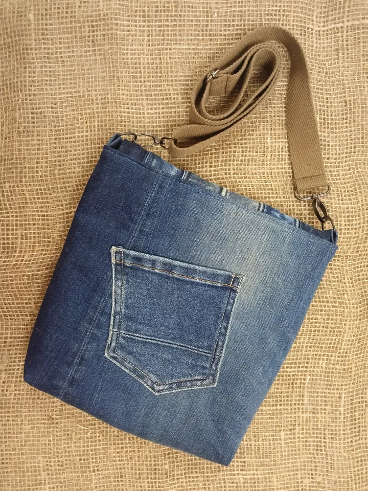 Denim messenger bag made of denim fabric with a denim belt flap. It has an external pocket on the back wall, 3 internal pockets and a patterned cotton lining.
