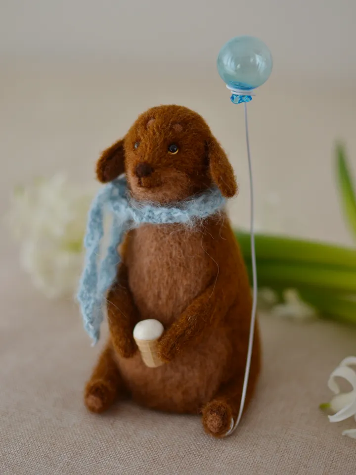 Handmade toy. Dachshund puppy in a scarf, with ice cream and a ball
