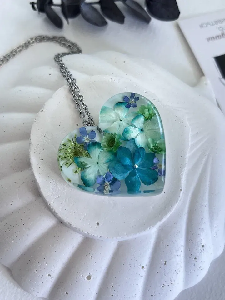 Women's pendant around the neck made of epoxy resin with real flowers in the shape of a heart