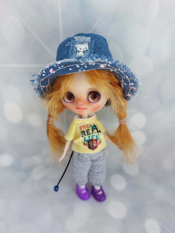 A little Blythe doll with red hair and brown eyes. a girl in a denim outfit.