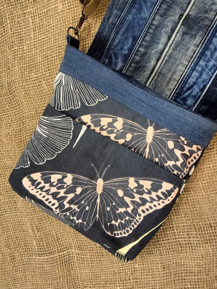 Denim messenger bag made of denim fabric with a denim belt flap. It has an external pocket on the back wall, 3 internal pockets and a patterned cotton lining.