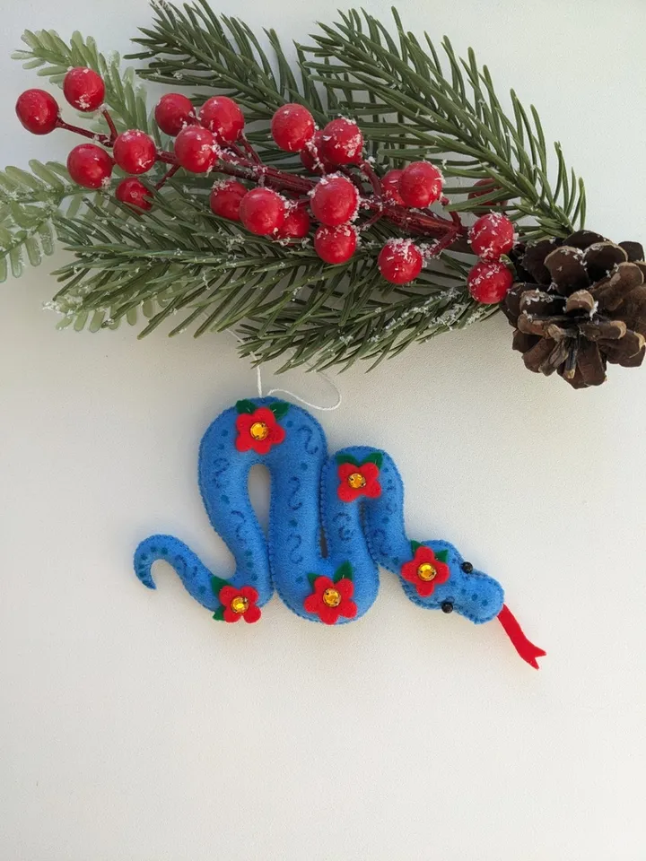 A blue snake in a red flower is a symbol of the new year 2025 according to the eastern calendar. Cute felt snake - Christmas tree decoration, Christmas gift