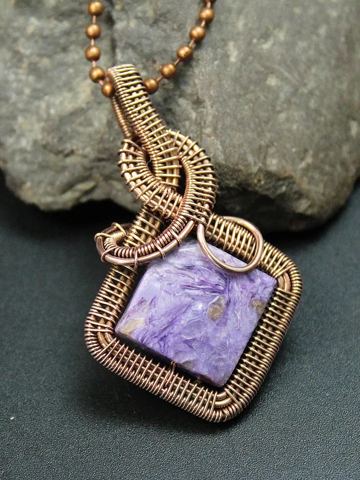 Handmade pendant of natural charoite and copper wire.