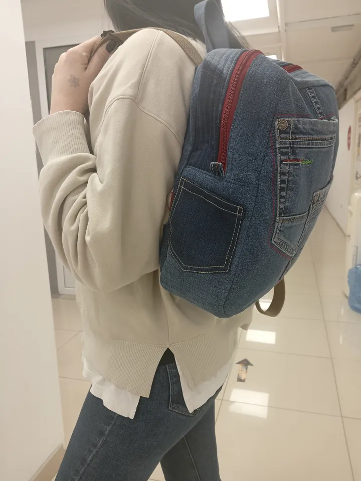 Casual unisex denim backpack made from recycled jeans, with 3 pockets outside and 3 pockets inside (1 with a zipper), strong 2-color strap on adjustable straps. Inside is synthetic fabric. The back and bottom is quilted.