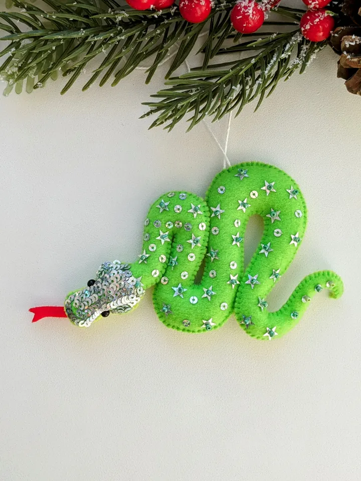 The green snake, the emerald snake, is the symbol of the new year 2025 according to the eastern calendar. Green snake with shiny scales felt Christmas tree decoration