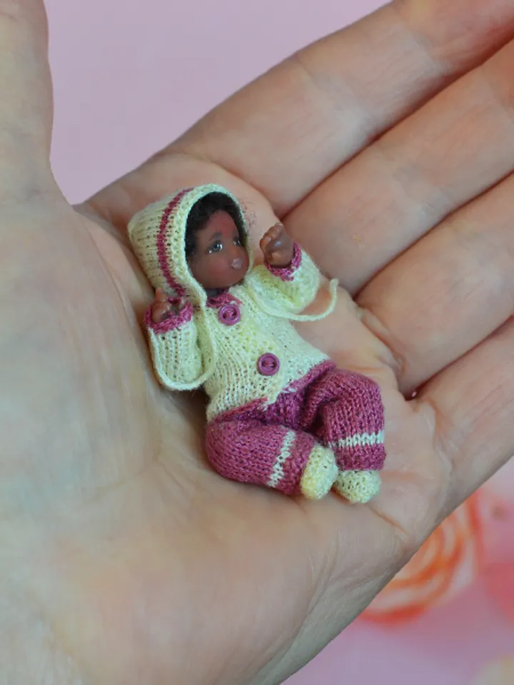 Miniature doll child in 12th scales. A baby for the dollhouse. Baby in a knitted suit.