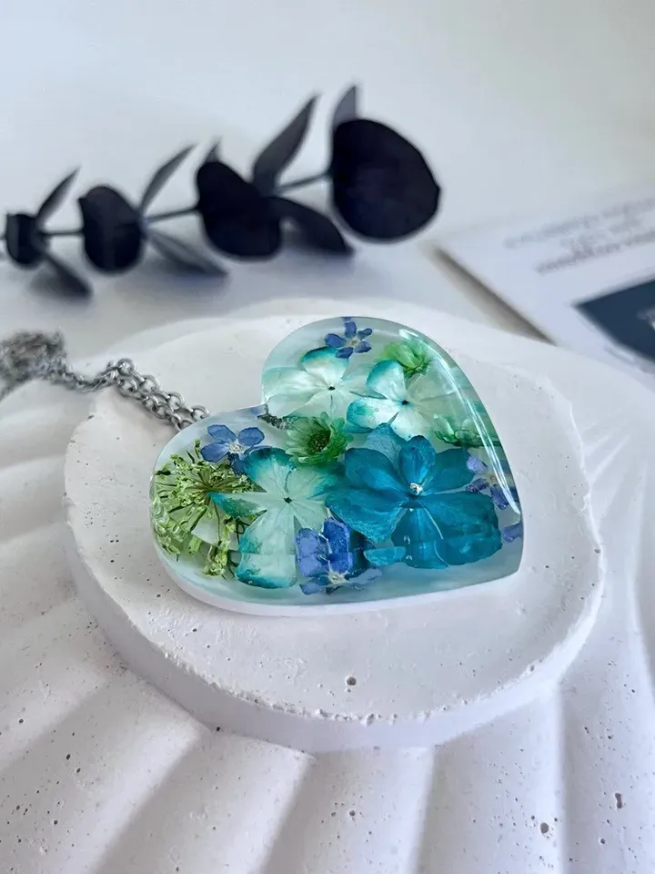 Women's pendant around the neck made of epoxy resin with real flowers in the shape of a heart