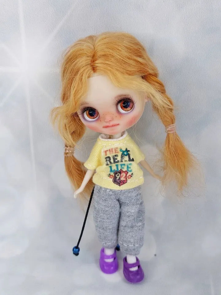 A little Blythe doll with red hair and brown eyes. a girl in a denim outfit.