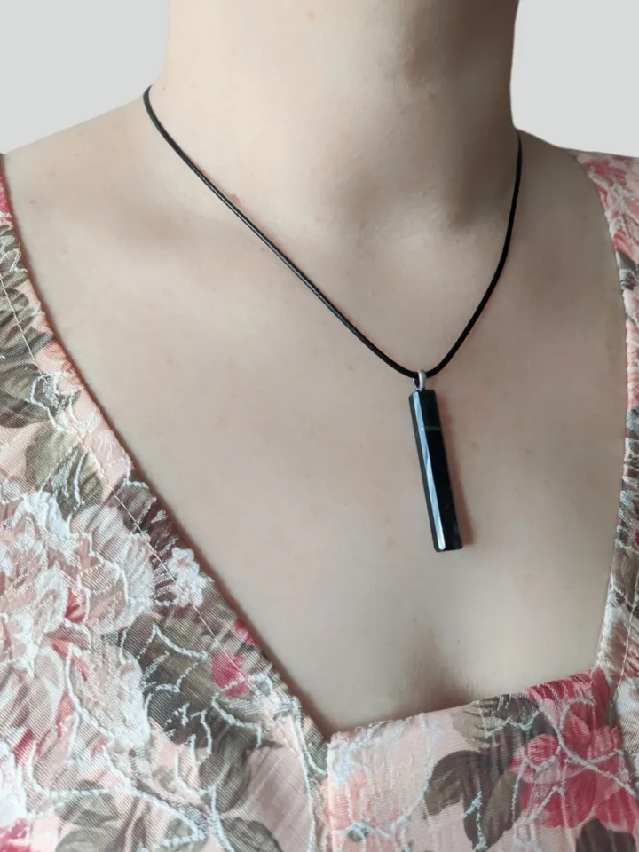 Rectangular pendant made of dark green jade in the shape of a column.