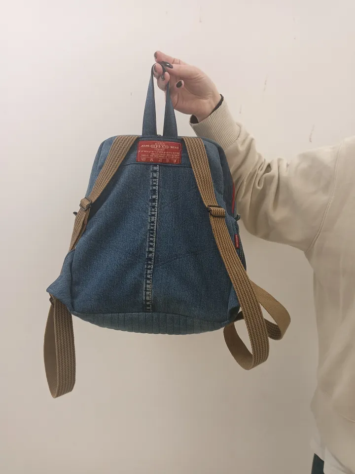 Casual unisex denim backpack made from recycled jeans, with 3 pockets outside and 3 pockets inside (1 with a zipper), strong 2-color strap on adjustable straps. Inside is synthetic fabric. The back and bottom is quilted.