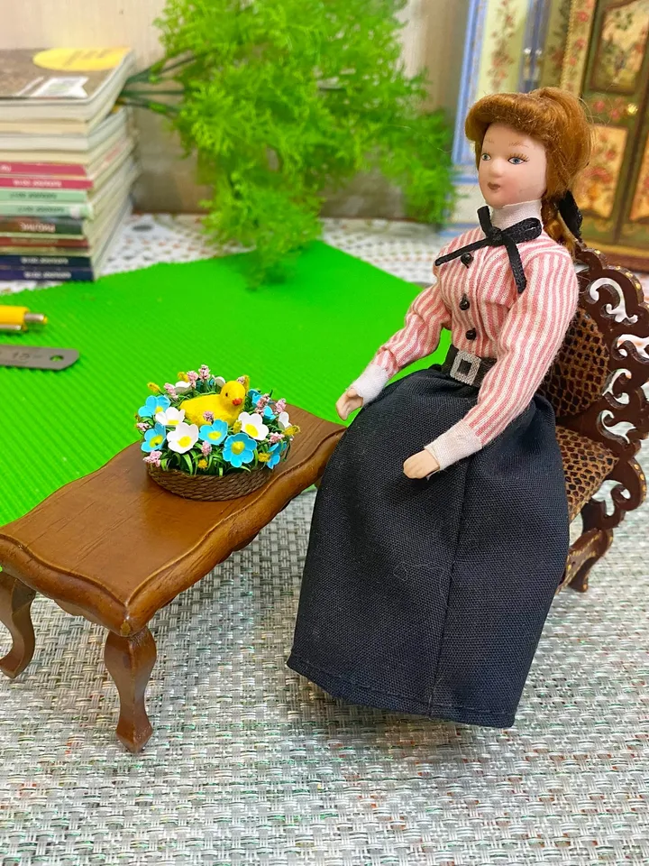 Easter miniature.Chicken in a basket with flowers.