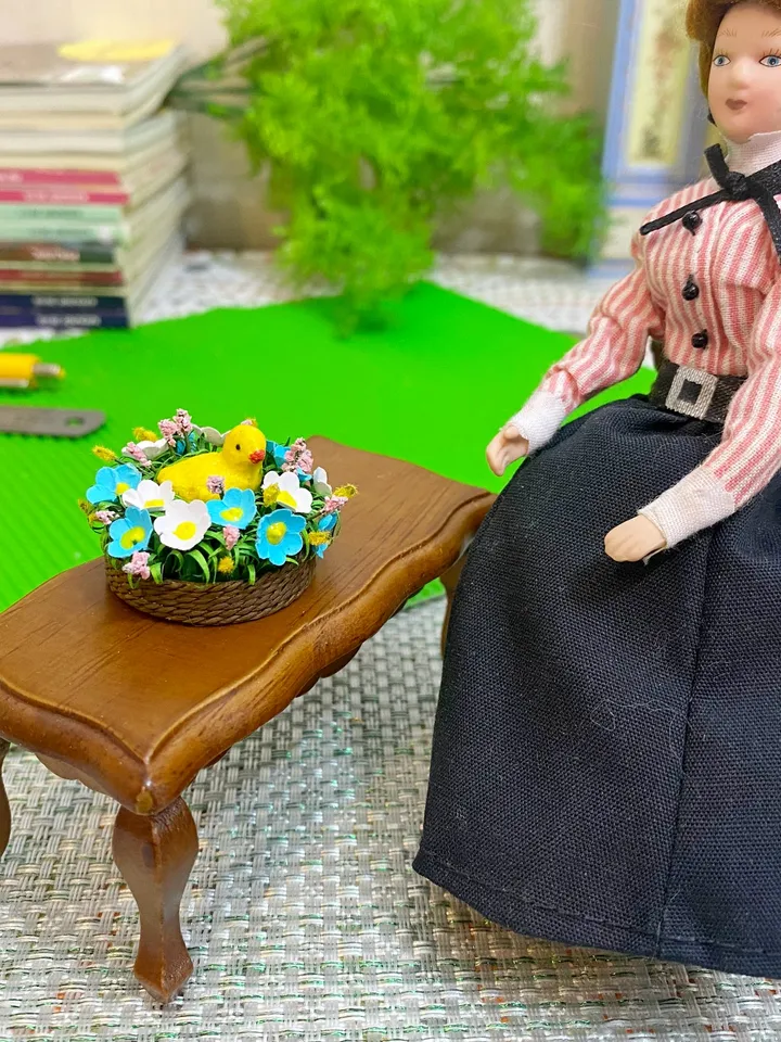 Easter miniature.Chicken in a basket with flowers.