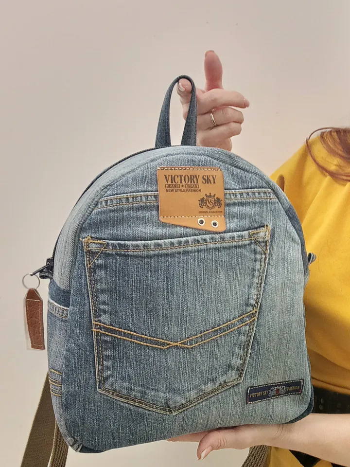 medium sized denim backpack made from recycled jeans for walking, studying, work, traveling. Backpack with 2 pockets outside and 3 pockets inside (1 with a zipper). Inside lining made of 100% cotton. Decorated with a label and a leather strip on the zippe