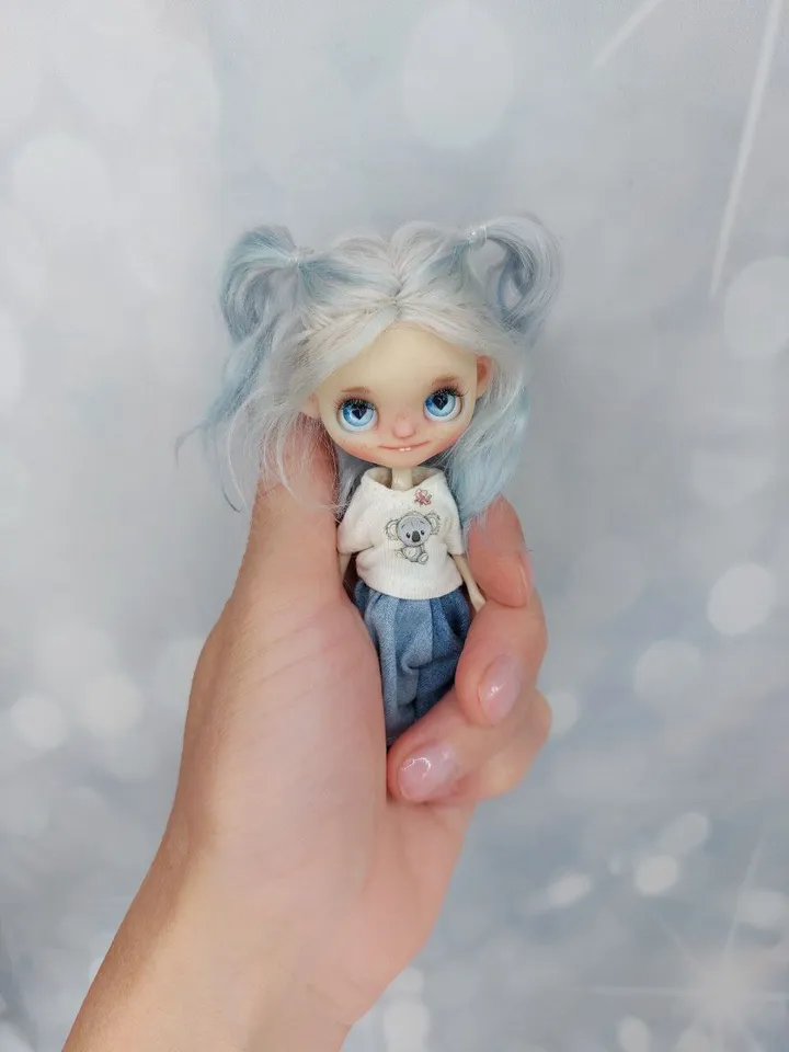 A small doll with blue hair. Interesting heart-shaped eyes.