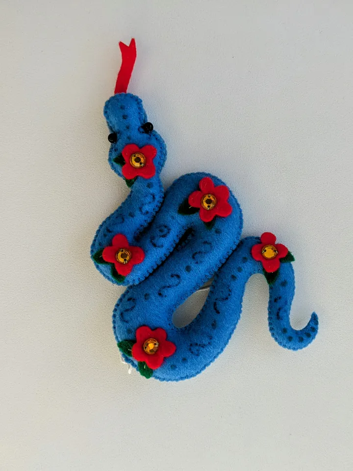 A blue snake in a red flower is a symbol of the new year 2025 according to the eastern calendar. Cute felt snake - Christmas tree decoration, Christmas gift