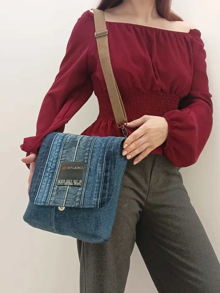 Denim messenger bag made of denim fabric with a denim belt flap. It has an external pocket on the back wall, 3 internal pockets and a patterned cotton lining.