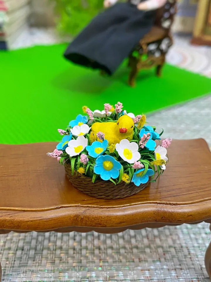 Easter miniature.Chicken in a basket with flowers.