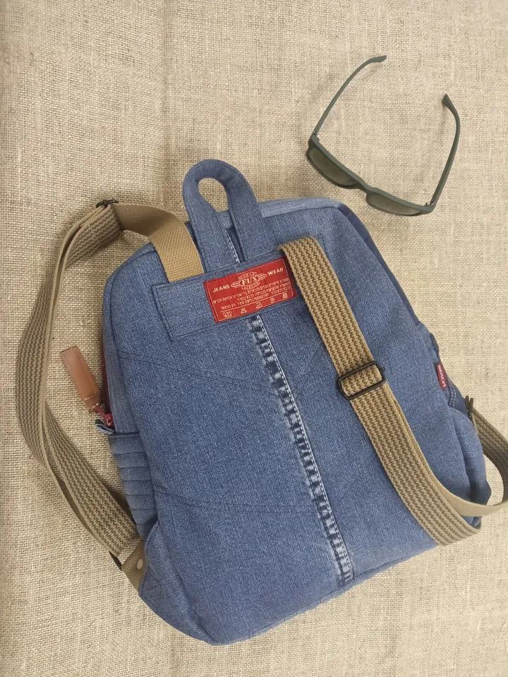 Casual unisex denim backpack made from recycled jeans, with 3 pockets outside and 3 pockets inside (1 with a zipper), strong 2-color strap on adjustable straps. Inside is synthetic fabric. The back and bottom is quilted.