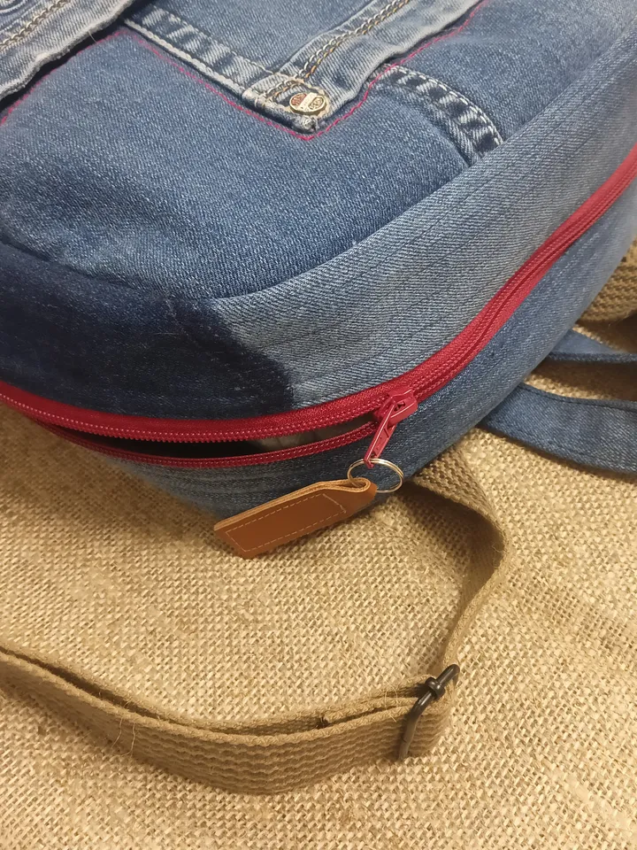 Casual unisex denim backpack made from recycled jeans, with 3 pockets outside and 3 pockets inside (1 with a zipper), strong 2-color strap on adjustable straps. Inside is synthetic fabric. The back and bottom is quilted.