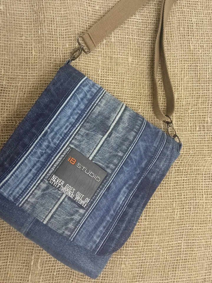 Denim messenger bag made of denim fabric with a denim belt flap. It has an external pocket on the back wall, 3 internal pockets and a patterned cotton lining.