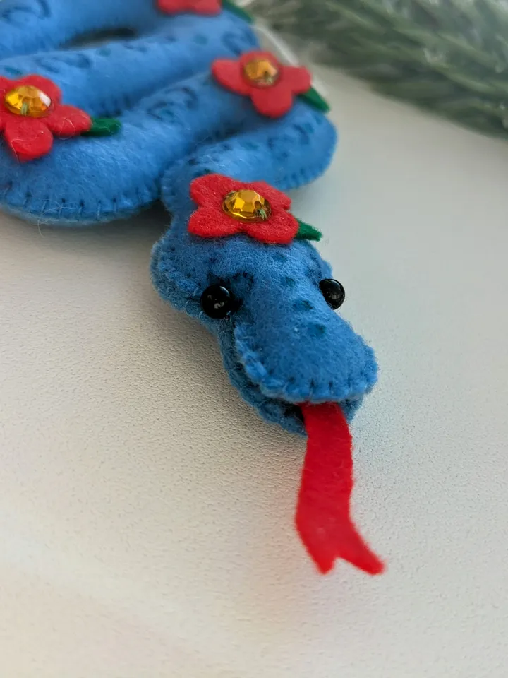 A blue snake in a red flower is a symbol of the new year 2025 according to the eastern calendar. Cute felt snake - Christmas tree decoration, Christmas gift