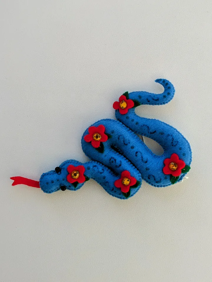 A blue snake in a red flower is a symbol of the new year 2025 according to the eastern calendar. Cute felt snake - Christmas tree decoration, Christmas gift