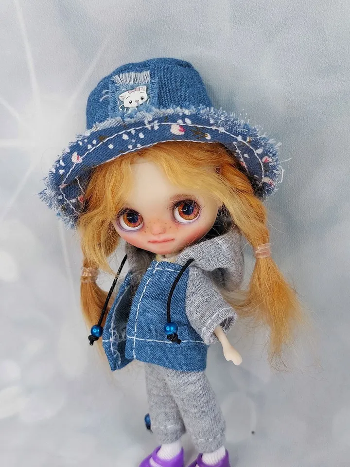 A little Blythe doll with red hair and brown eyes. a girl in a denim outfit.