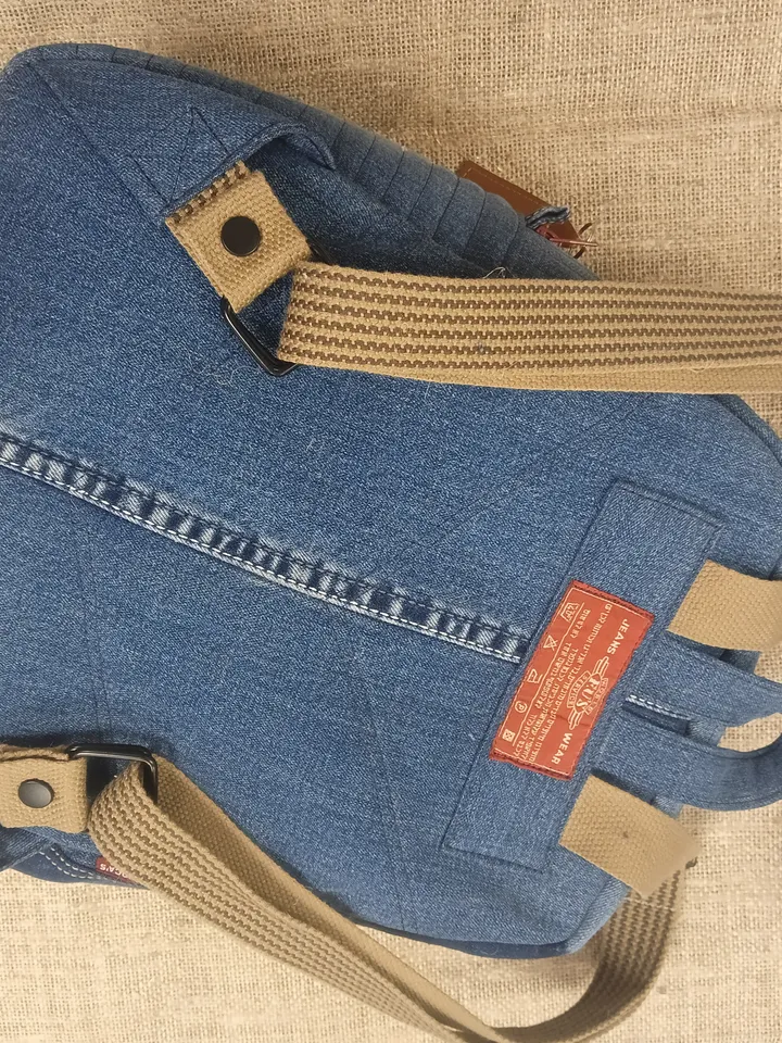 Casual unisex denim backpack made from recycled jeans, with 3 pockets outside and 3 pockets inside (1 with a zipper), strong 2-color strap on adjustable straps. Inside is synthetic fabric. The back and bottom is quilted.
