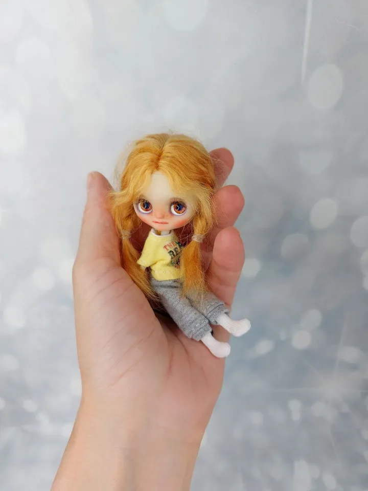A little Blythe doll with red hair and brown eyes. a girl in a denim outfit.