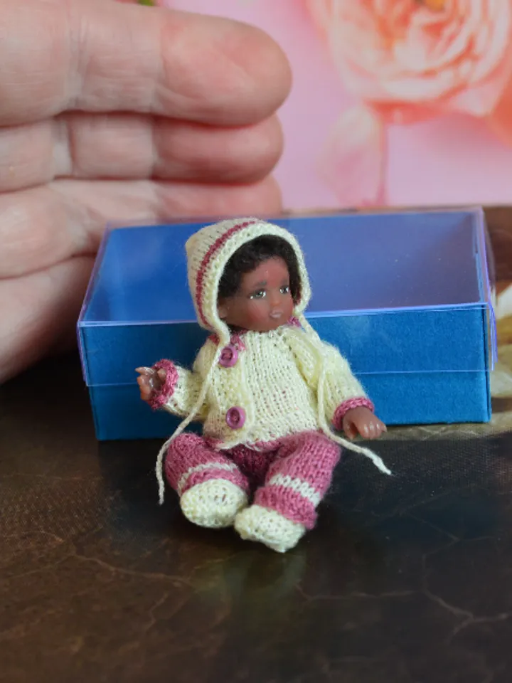 Miniature doll child in 12th scales. A baby for the dollhouse. Baby in a knitted suit.