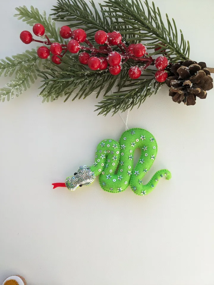 The green snake, the emerald snake, is the symbol of the new year 2025 according to the eastern calendar. Green snake with shiny scales felt Christmas tree decoration